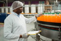 Trabalhador masculino sério examinando garrafas na fábrica de suco — Fotografia de Stock