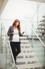Femme d'affaires enceinte descendant les escaliers dans le bureau — Photo de stock