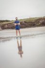 Спортсмен стоїть з обіймами, схрещеними на пляжі — стокове фото