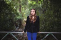 Retrato de mulher em pé na ponte da passarela na floresta — Fotografia de Stock