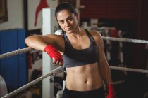 Впевнена жінка-боксер, спираючись на боксерське кільце в фітнес-студії — стокове фото