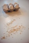 Яйцо в коробке и муке на кухонном столе дома — стоковое фото