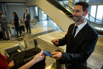 Geschäftsmann übergibt Bordkarte an weibliches Personal im Flughafen-Terminal — Stockfoto
