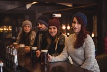 Retrato de amigos segurando copos de cerveja no balcão do bar — Fotografia de Stock