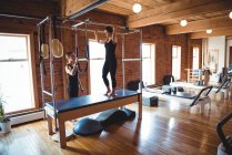 Formateur aidant les femmes à pratiquer le pilates dans un studio de fitness — Photo de stock
