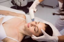 Dermatologo dare massaggio facciale al paziente attraverso soniclifting in clinica — Foto stock