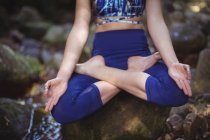Woman meditating in lotus position in forest — Stock Photo