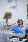 Odontoiatra che esamina il paziente maschile con strumenti in clinica — Foto stock