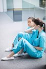 Грустные медсестры сидят на коридоре в больнице — стоковое фото
