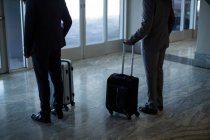 Ділові люди з багажем, що стоять в зоні очікування в аеропорту — стокове фото