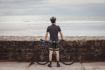 Вид ззаду спортсмена, що стоїть з велосипедом на дорозі — стокове фото