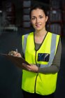 Портрет впевненого працівника-жінки, що відзначає на кишені на складі — стокове фото