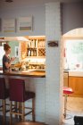 Donna che usa il telefono cellulare mentre prende il caffè in cucina a casa — Foto stock