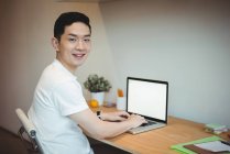 Портрет улыбающегося бизнесмена, работающего на ноутбуке в офисе — стоковое фото