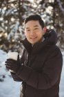 Porträt eines lächelnden Mannes in warmer Kleidung, der im Winter eine Kaffeetasse hält — Stockfoto