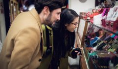 Happy couple standing at gifts counter in supermarket — Stock Photo