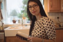 Ritratto di donna che legge un libro in cucina a casa — Foto stock
