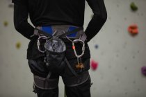 Partie médiane de l'homme debout contre un mur d'escalade artificiel dans la salle de gym — Photo de stock