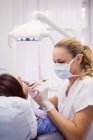 Dentiste examinant une patiente en clinique — Photo de stock
