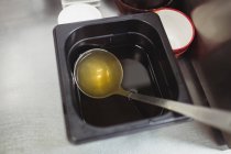 Oil in container with ladle in restaurant kitchen — Stock Photo