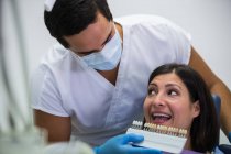 Dentista esaminando paziente femminile con paralumi dentali presso la clinica dentale — Foto stock