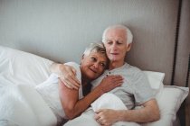 Старшая пара отдыхает на кровати в спальне — стоковое фото