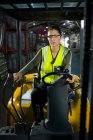 Portrait of confident female worker driving forklift in warehouse — Stock Photo
