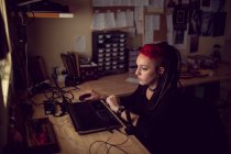 Женщина парикмахер с помощью ноутбука в магазине дредов — стоковое фото