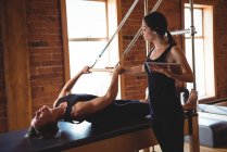 Treinador com tablet digital ajudando a mulher enquanto pratica pilates no estúdio de fitness — Fotografia de Stock