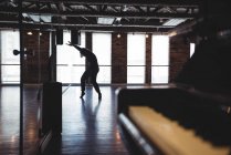 Женщина практикует танец в танцевальной студии с фортепиано — стоковое фото