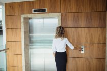 Rear view of businesswoman waiting for a lift in office — Stock Photo