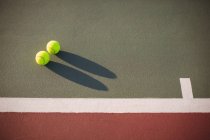 Крупный план теннисных мячей на корте с тенью — стоковое фото