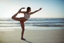 Mulher realizando ioga na praia em um dia ensolarado — Fotografia de Stock