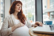 Embarazada mujer de negocios usando laptop en oficina cafetería - foto de stock