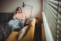 Frau telefoniert mit Handy, während sie sich zu Hause auf dem Sofa entspannt — Stockfoto