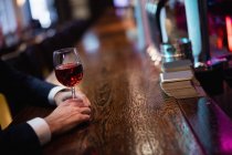 Hands of businessman sitting in bar counter with glass of wine at bar — Stock Photo