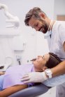 Dentista sorridente durante l'esame paziente in clinica — Foto stock