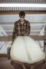 Чоловік робить дошку для серфінгу в інтер'єрі майстерні — стокове фото