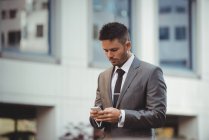 Businessman using mobile phone near office building — Stock Photo