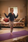 Chica realizando yoga en la sala de estar en casa - foto de stock