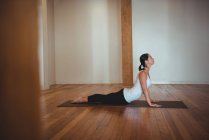 Femme pratiquant la pose de yoga cobra dans un studio de fitness — Photo de stock