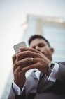 Крупним планом руки бізнесмена, використовуючи мобільний телефон біля офісної будівлі — стокове фото