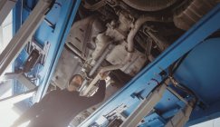 Meccanico esaminando una macchina in officina di riparazione — Foto stock