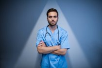 Вид спереду медсестри чоловічої статі, що стоїть в коридорі лікарні зі схрещеними руками — стокове фото