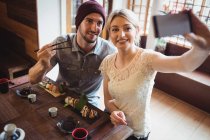 Couple taking selfie while having sushi in restaurant — Stock Photo