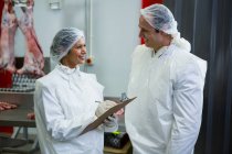 Butchers interacting in meat factory interior — Stock Photo