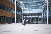 Gruppo di uomini d'affari che camminano fuori dall'ingresso di un edificio per uffici — Foto stock
