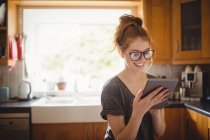 Усміхнена жінка використовує цифровий планшет на кухні вдома — стокове фото