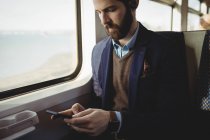 Бизнесмен, пользующийся мобильным телефоном во время поездов — стоковое фото