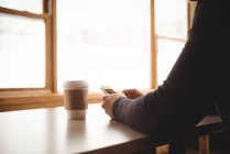 Мужчина на телефоне пьет кофе на горнолыжном курорте — стоковое фото
